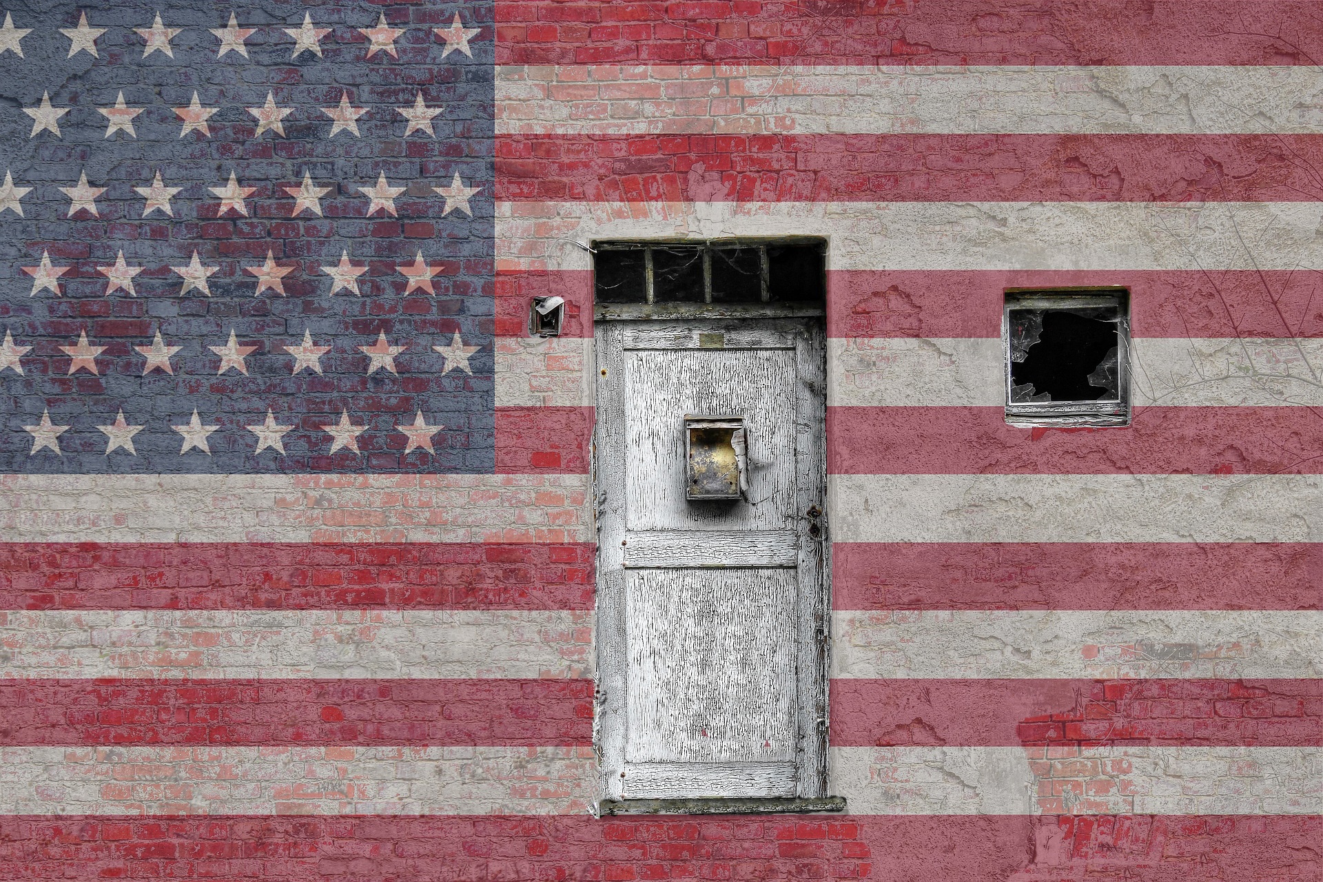 american flag painted on the side of a brick building with a door and shattered windows