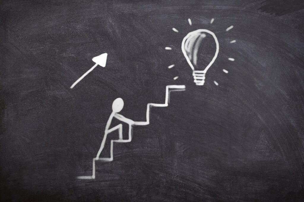 chalkboard drawing of a person climbing stairs toward a lightbulb with an arrow pointing upward