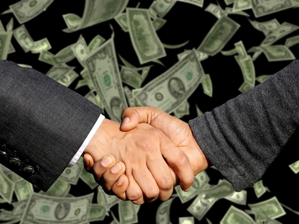 Picture of two people shaking hands, with US paper currency in the background.